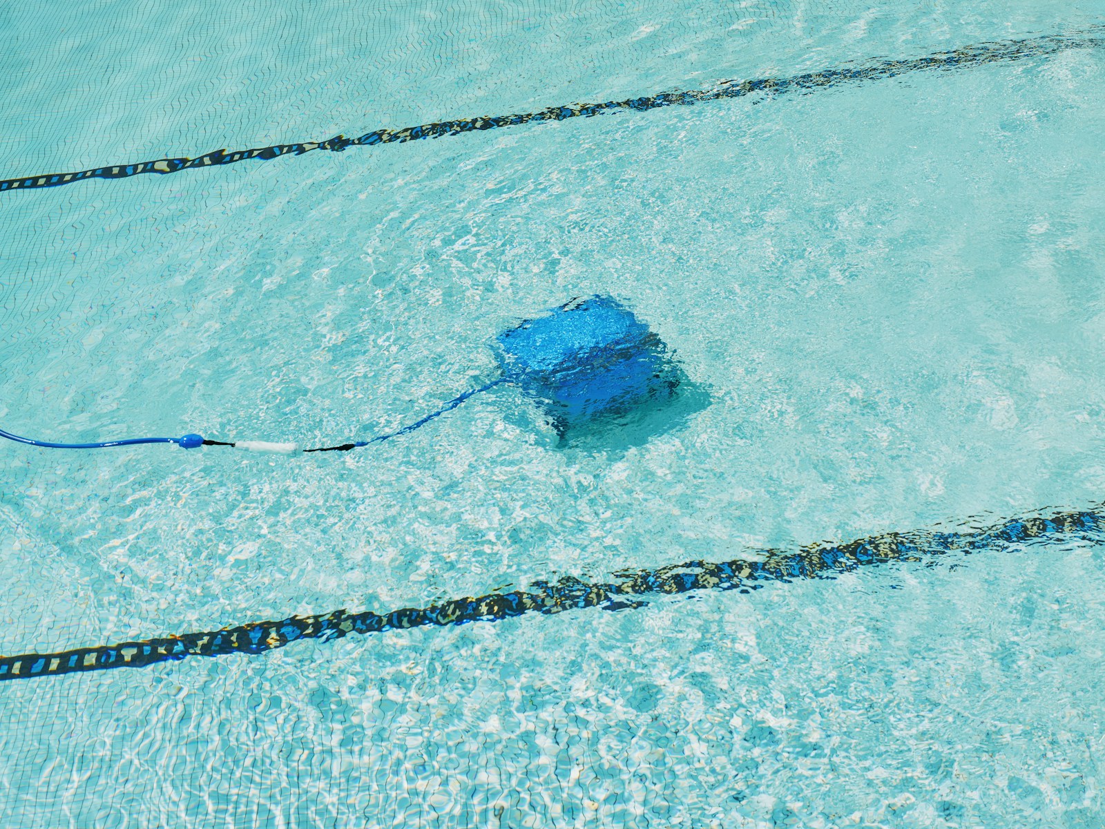 Robô limpador automático em ação em piscina de água cristalina